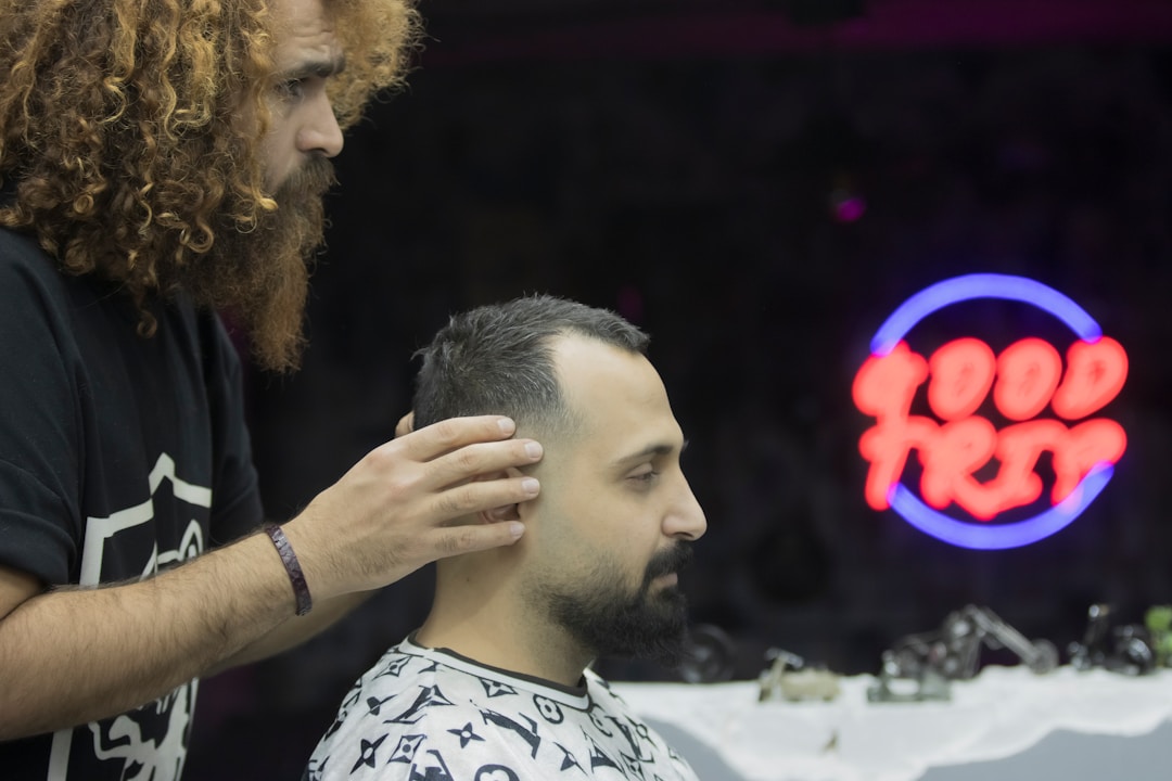 Professional barber cutting low fade haircut on curly hair client using specialized techniques for textured hair at modern Queens NYC barbershop