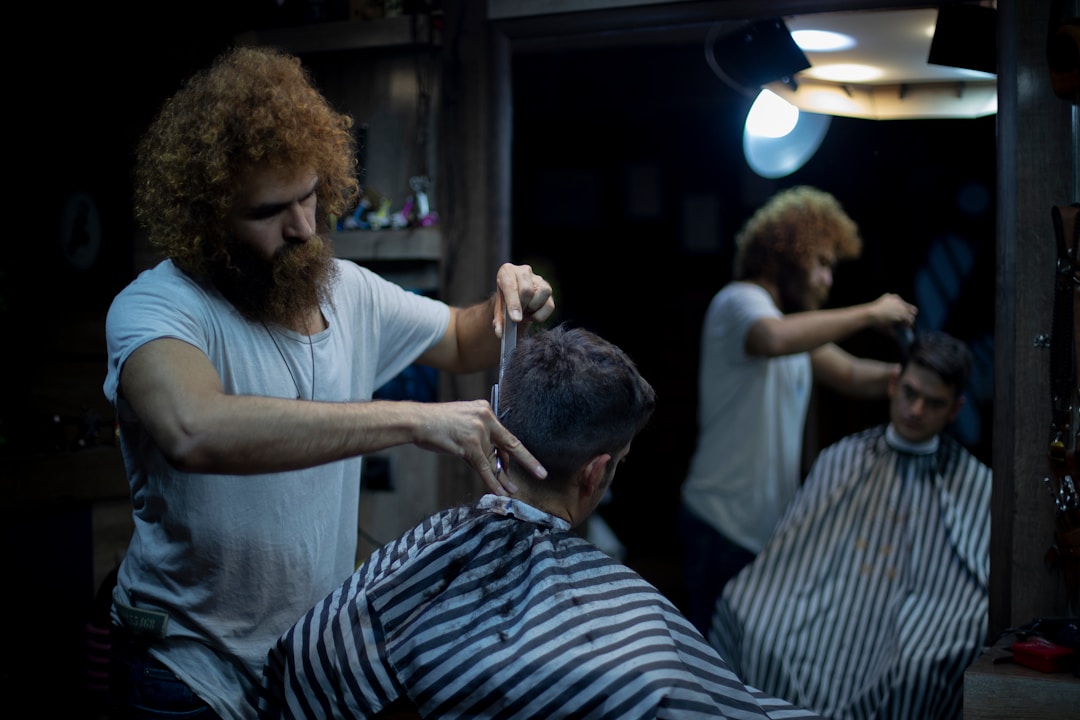 Professional barber styling curly hair low fade haircut demonstrating product application and curl definition techniques at Queens barbershop